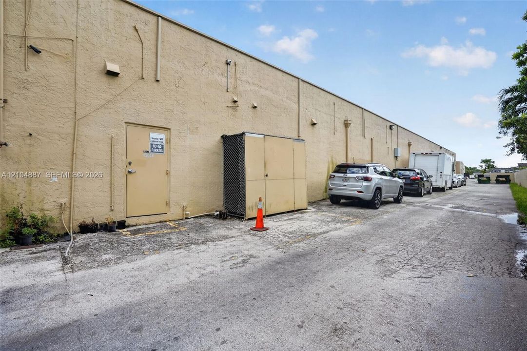 Stucco exterior building featuring a service entrance and paved alley access