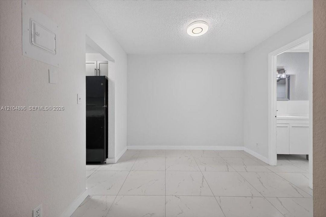 Large-format tile flooring with marble-pattern veining, flush-mount circular lighting fixture, and neutral wall finishes