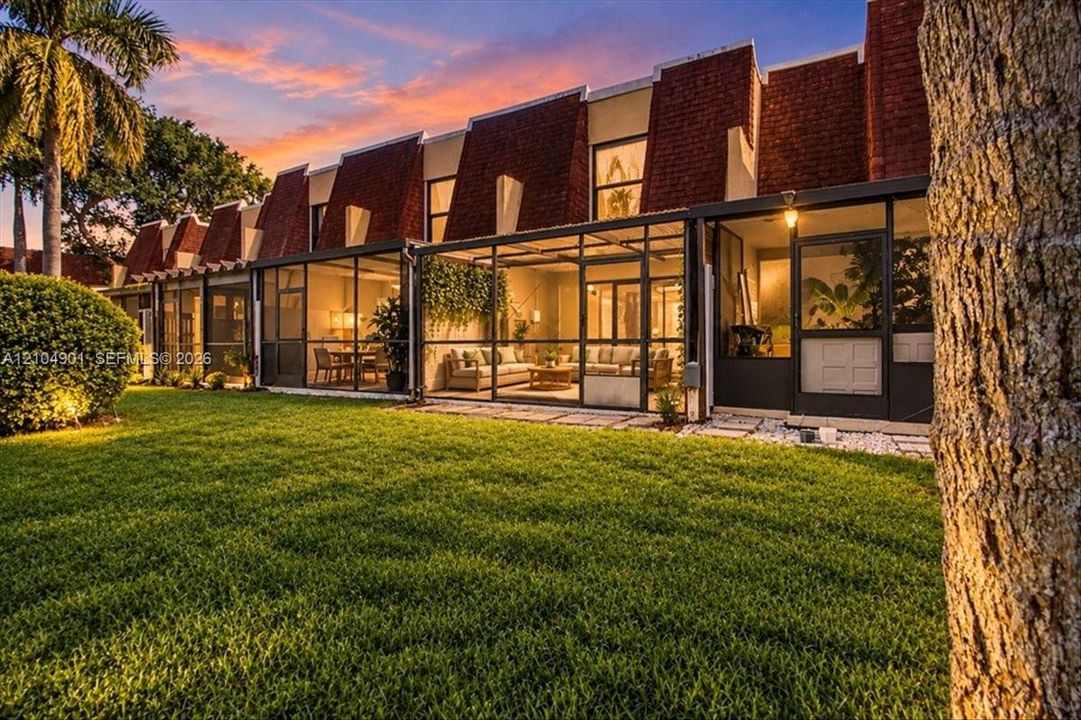 Exterior facade with tiered shingle roofline, expansive screened-in lanai, and manicured lawn