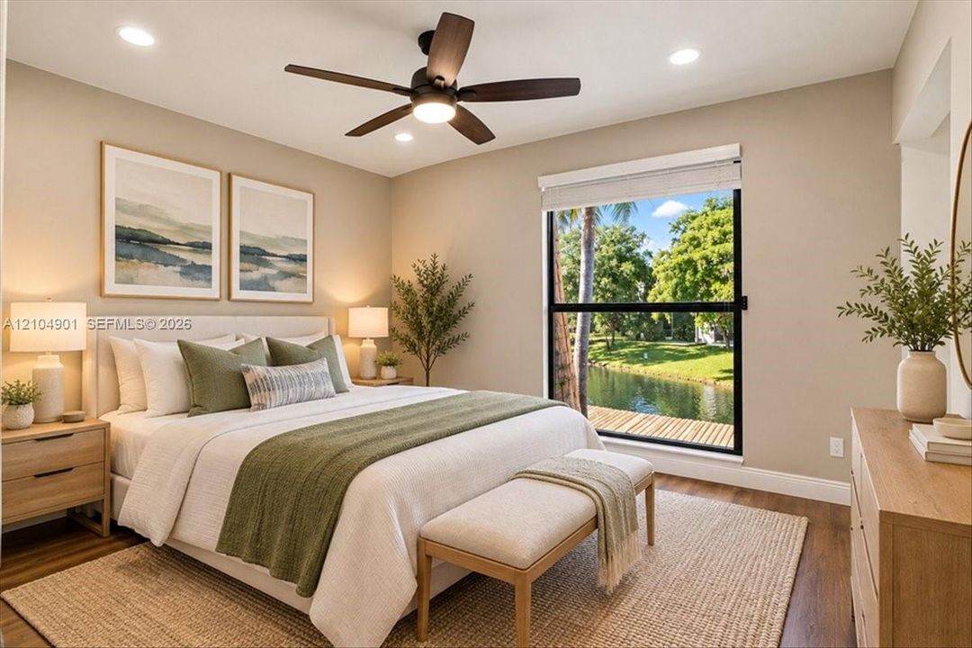 Wood-finish flooring, recessed lighting, dark-finish ceiling fan, and large picture window with water scenery
