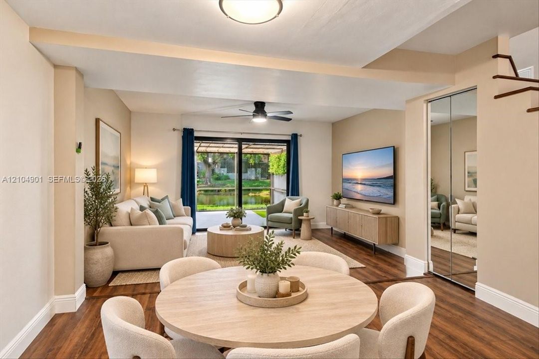 Open-concept interior featuring wood-finish flooring, sliding glass patio doors, a ceiling fan, and mirrored closet doors