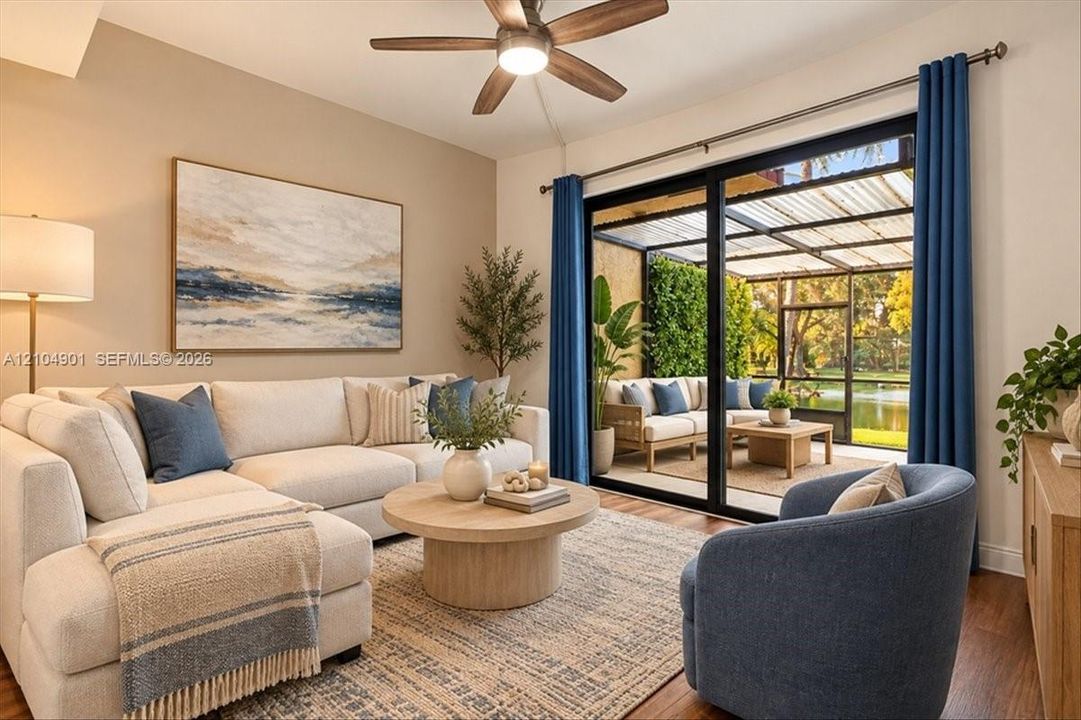 Black-framed sliding glass doors opening to a screened-in lanai, wood-finish flooring, and a ceiling fan with integrated lighting