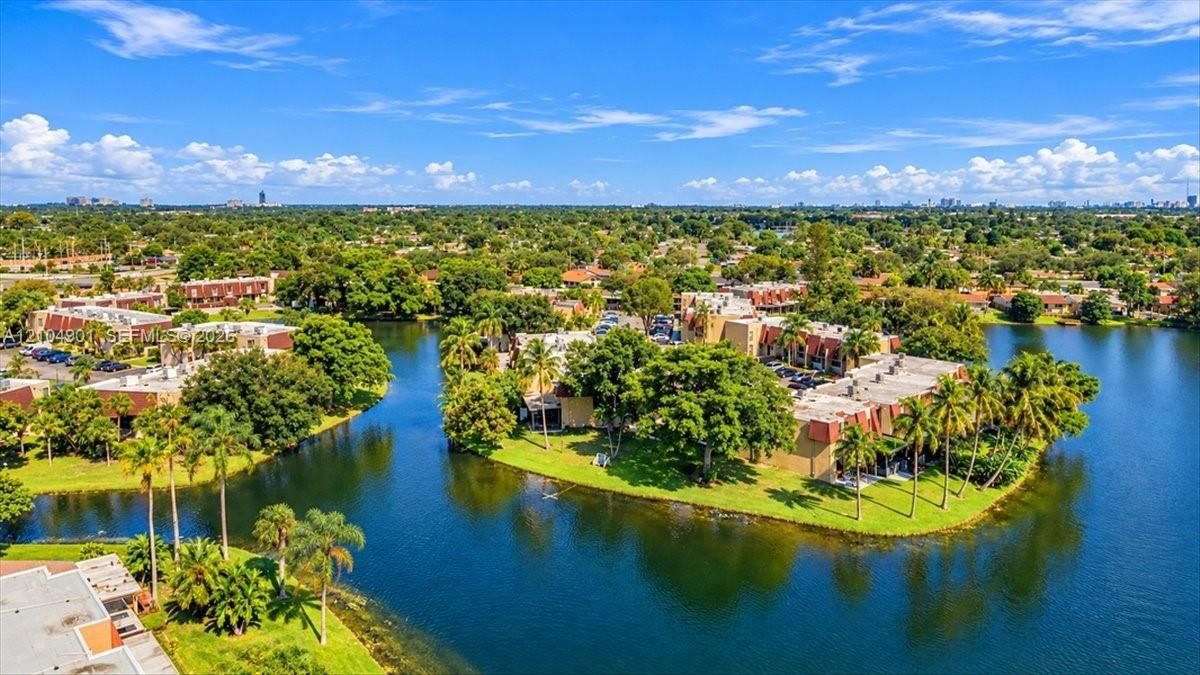 Waterfront residential complex featuring multiple buildings, manicured lawns, mature palm trees, and direct access to a canal