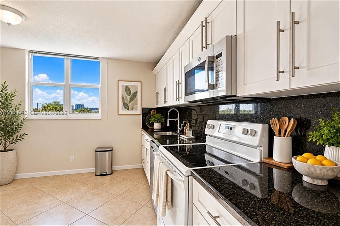 Kitchen featuring white shaker-style cabinetry, dark stone countertops, tile flooring, built-in stainless steel microwave, and white range