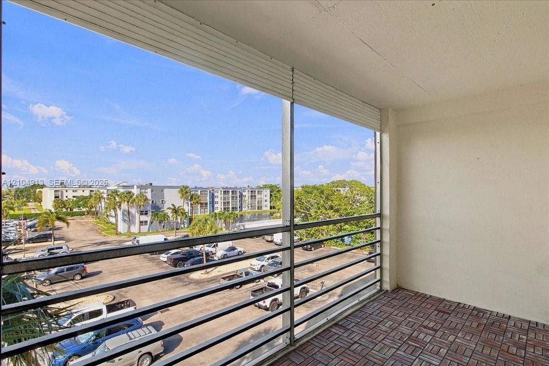 Screened-in balcony featuring metal railing and interlocking tile flooring