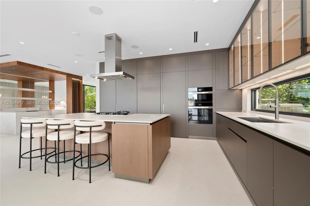Sleek kitchen with a central island, integrated stainless steel appliances, and a wall of built-in cabinetry