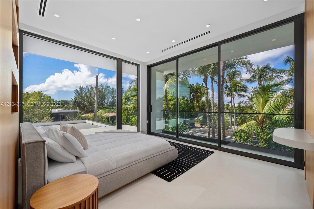 Expansive floor-to-ceiling windows, recessed lighting, neutral tone flooring, wood-finish wall panels, and a built-in wall-mounted desk