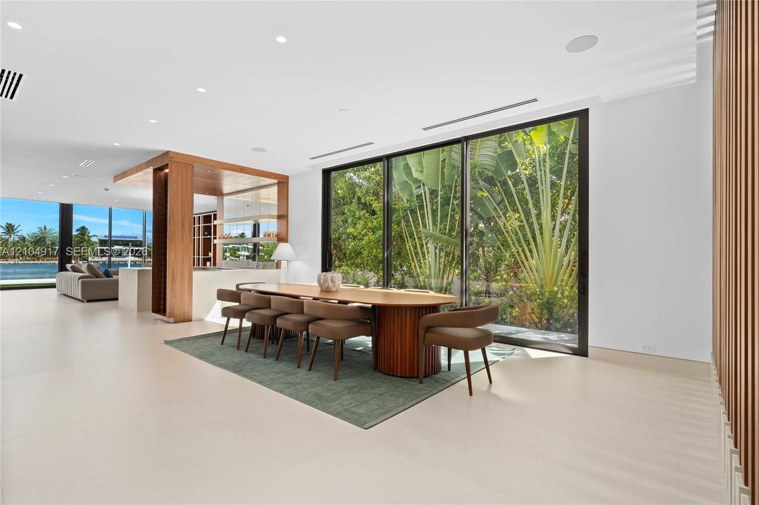 Expansive interior with light-toned flooring, full-height windows, a built-in wood-finish divider, and recessed lighting