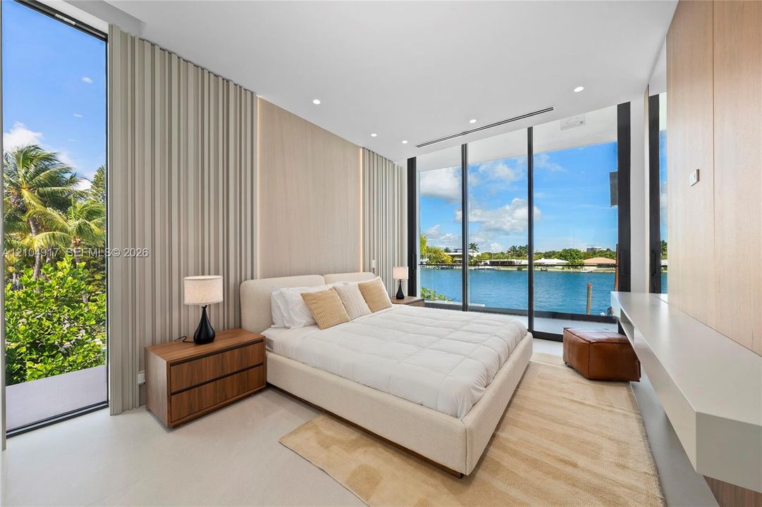 Waterfront setting with expansive floor-to-ceiling windows, recessed lighting, wood-finish wall panels, and a built-in display shelf
