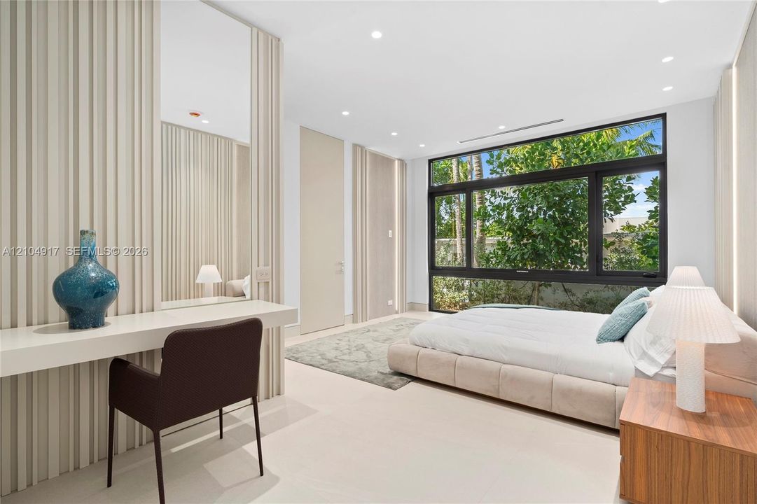 Expansive window system with dark framing, recessed lighting, light-toned flooring, and a built-in vanity with mirror