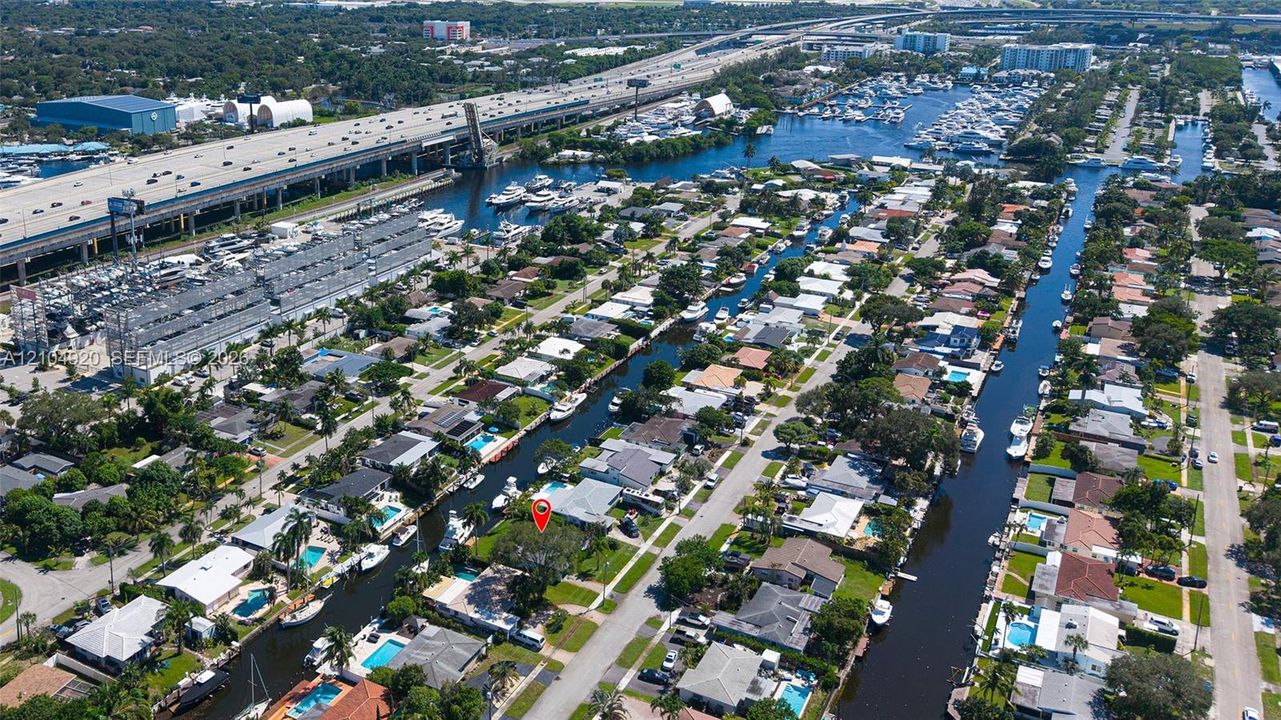 Aerial perspective of the waterfront residential property featuring direct canal access, a private dock, and mature landscaping