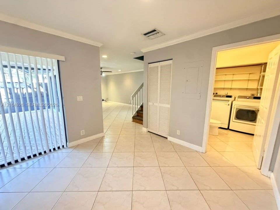 Interior space featuring large-format tile flooring, louvered-door closet, and sliding glass door with vertical blinds
