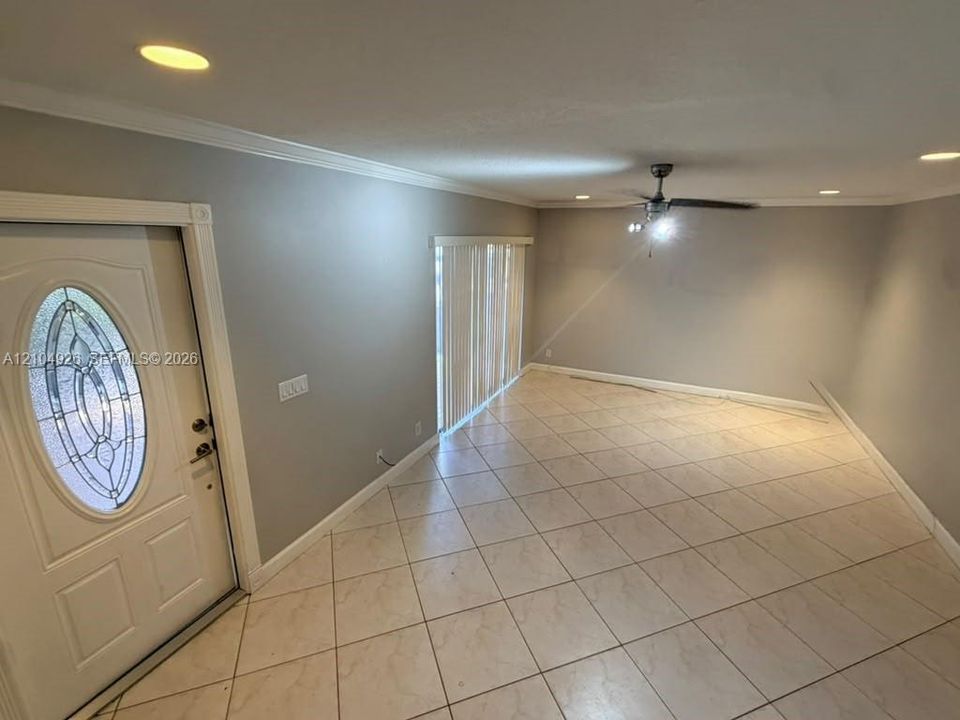 Entryway featuring a white door with an oval decorative glass insert, neutral-toned tile flooring, recessed ceiling lighting, and a ceiling fan