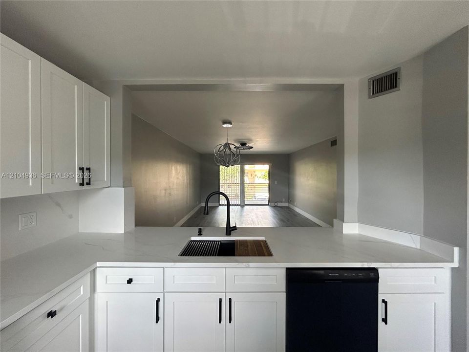 Kitchen featuring white shaker-style cabinetry, white countertops with grey veining, a matte black high-arc faucet, and an integrated drop-in sink