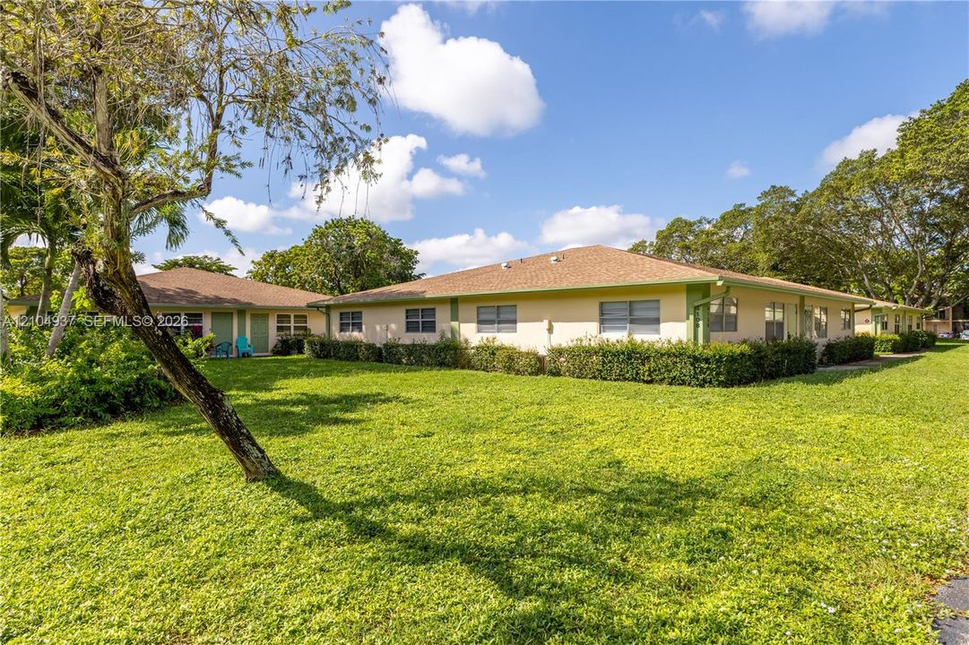 Single-story exterior featuring a hip roof, stucco siding, horizontal sliding windows, and established perimeter shrubbery set on a expansive lawn