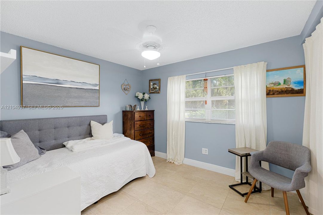 Neutral-toned tile flooring, large multi-pane window, and central ceiling fan with integrated lighting