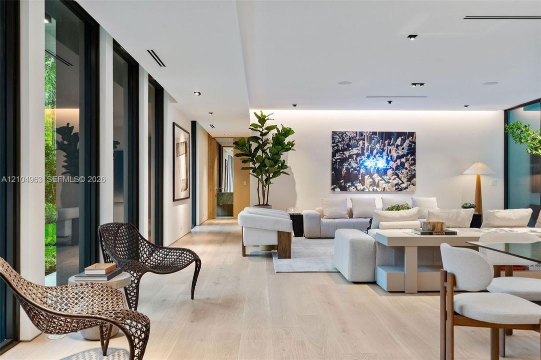 Wide-plank wood-finish flooring, floor-to-ceiling glass panels, recessed architectural lighting, and cove ceiling accent lighting