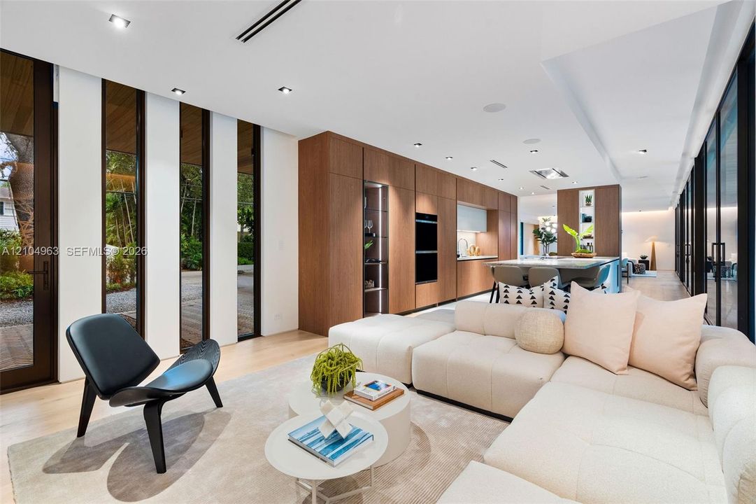 Open-concept space featuring wood-finish flooring, floor-to-ceiling windows, recessed lighting, and full-height wood cabinetry with built-in wall ovens