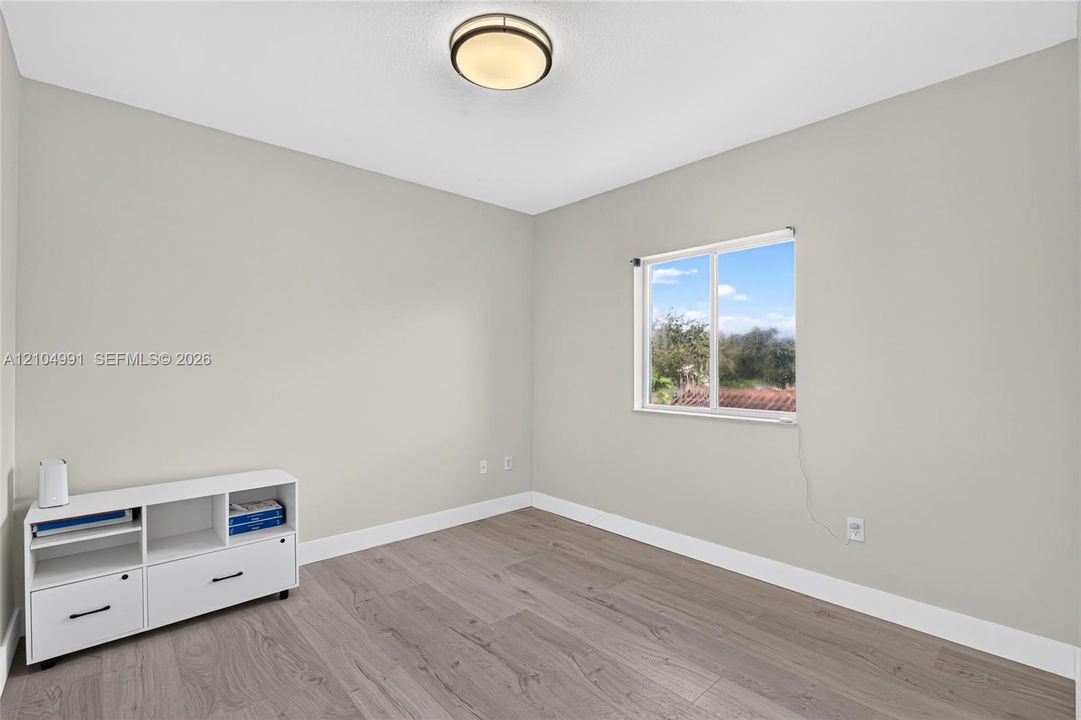 Neutral-toned interior featuring wood-finish flooring, a flush-mount ceiling light fixture, and a single-hung window