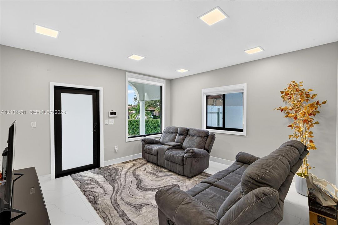Interior space featuring neutral wall paint, recessed lighting, large-format tile flooring, and a contrast-framed exterior door