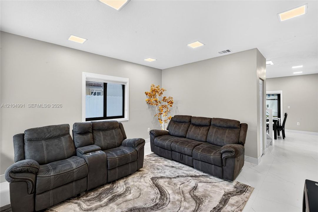 Neutral wall color, recessed ceiling lighting, and large-format tile flooring