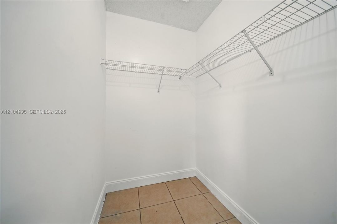 Storage area featuring ceramic tile flooring, neutral wall finishes, and integrated white wire shelving
