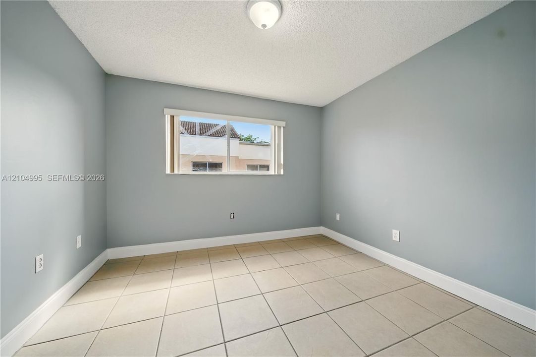 Room featuring neutral wall tones, large-format tile flooring, and a window with horizontal blinds