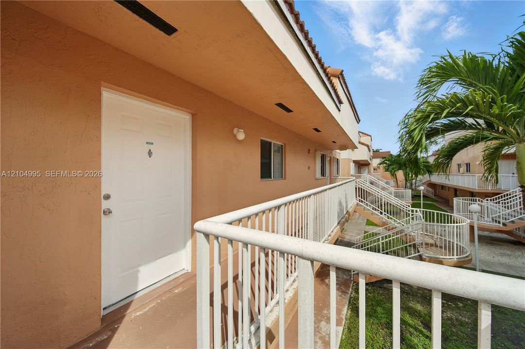 Stucco exterior finish with white entry door and white metal railing along the walkway