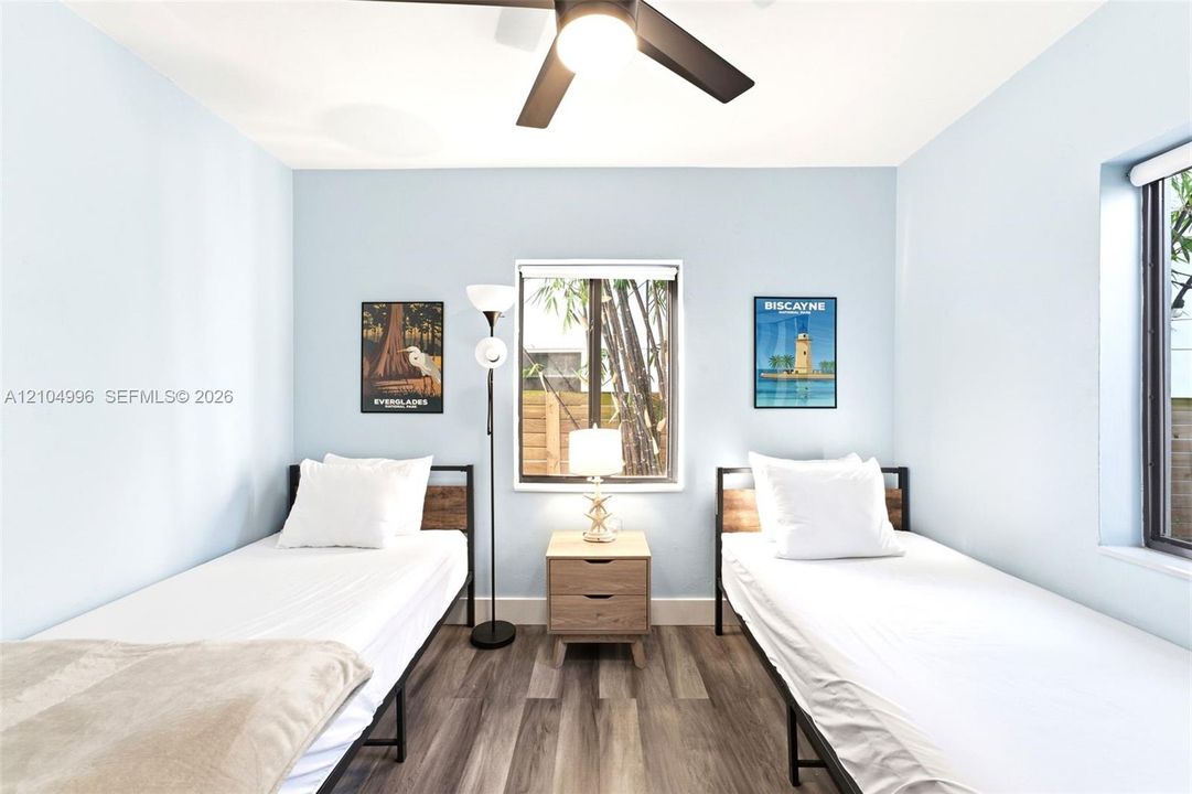 Wood-finish flooring, light blue interior paint, central ceiling fan with integrated lighting, and dual exterior-facing windows