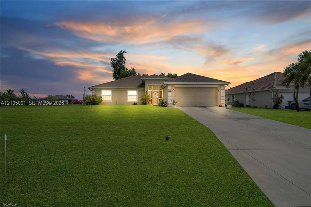 Single-story stucco exterior with a hip roof, featuring an attached two-car garage, concrete driveway, and expansive lawn