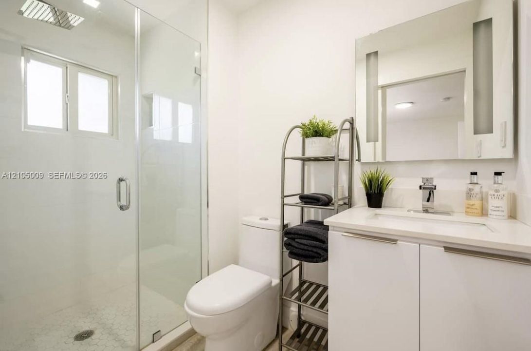 Glass-enclosed shower with white tiled walls and a hex-tile floor