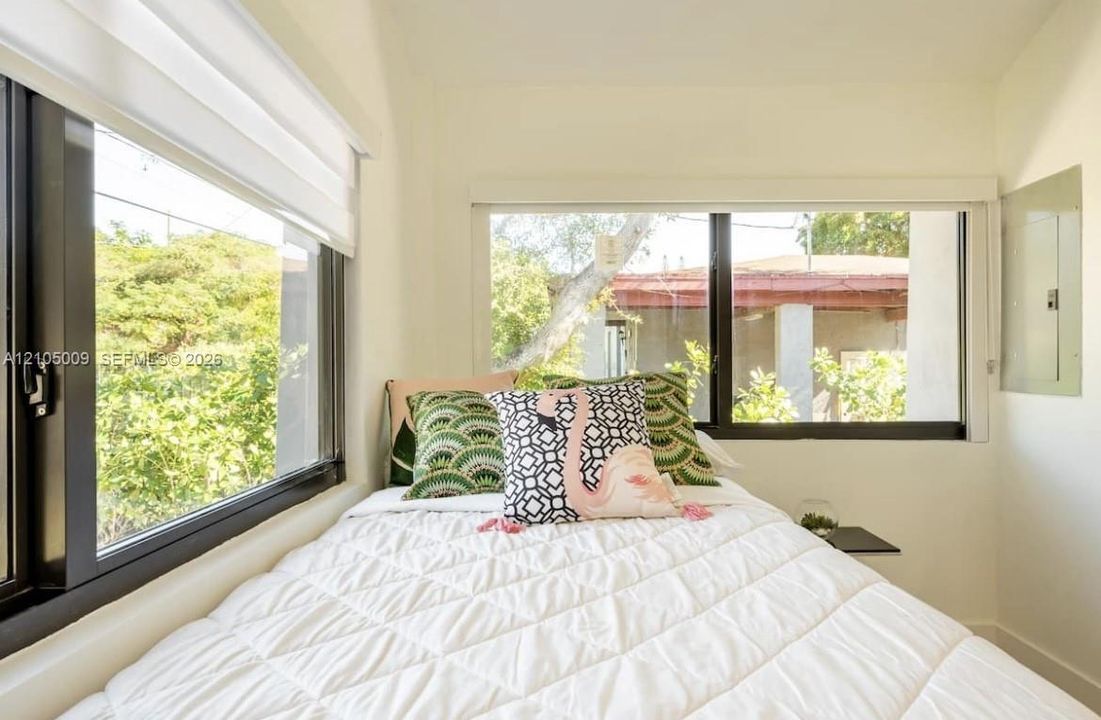 Dual windows with black frames and white window treatments