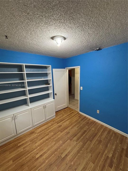 Built-in white cabinetry with open shelving, wood-finish flooring, and overhead lighting