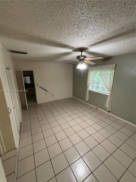 Tiled flooring throughout, ceiling fan with integrated lighting, and a window with natural light