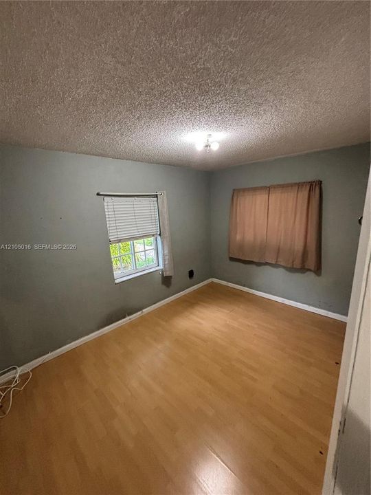 Wood-finish flooring with a ceiling-mounted light fixture, and window with blinds
