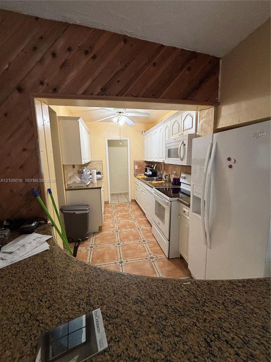 Kitchen featuring white upper and lower cabinetry, white appliances, and a built-in microwave