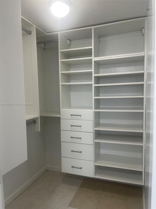 Custom built-in closet system featuring multiple shelving units, integrated drawers with linear pulls, and hanging rods