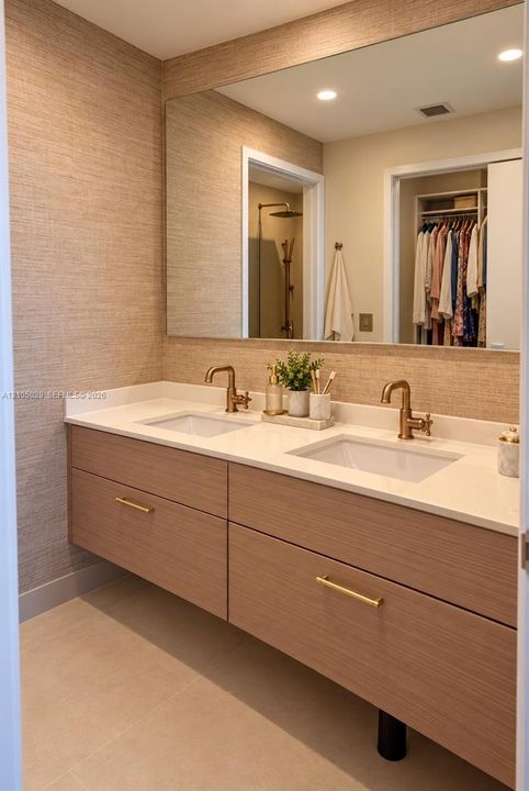 Floating vanity featuring a light wood finish, dual white rectangular sinks, brass-toned hardware, solid-surface countertop, and textured wall covering