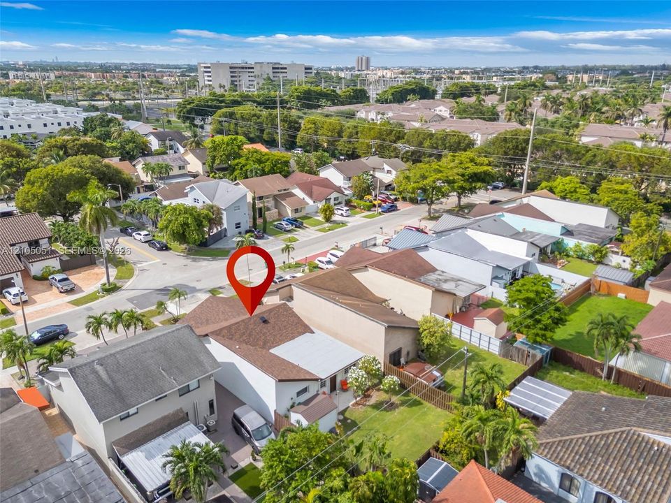 Aerial perspective featuring a multi-level residence with a multi-gabled roofline, private fenced yard, manicured lawn, and attached driveway