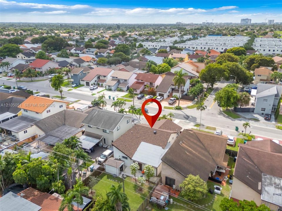 Aerial perspective featuring a shingled roof, fenced backyard, and mature landscaping