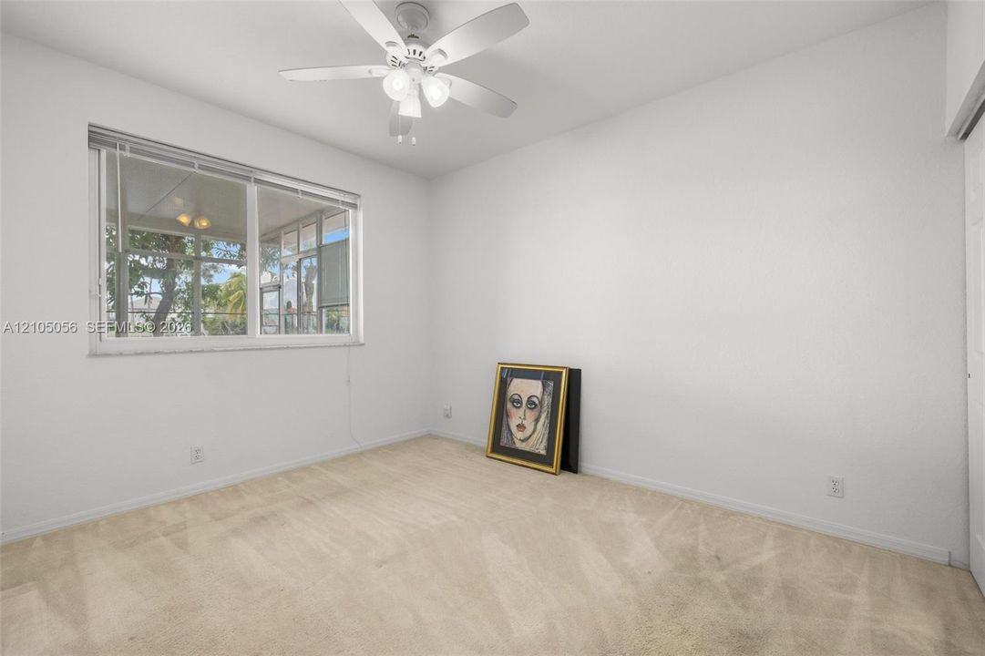 Neutral-toned wall-to-wall carpeting, white interior walls, white-finished ceiling fan with integrated lighting, and a large multi-pane window with views to the lake at downstairs bedroom