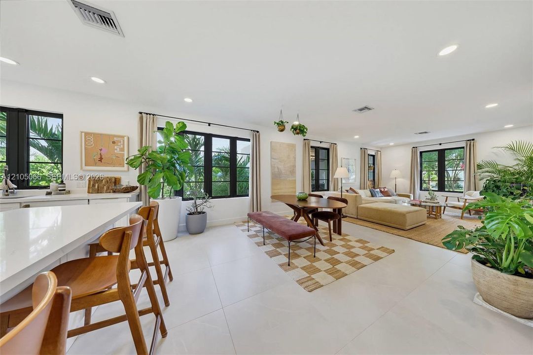 Open-concept interior featuring large-format tile flooring, recessed lighting, and multiple windows with black trim