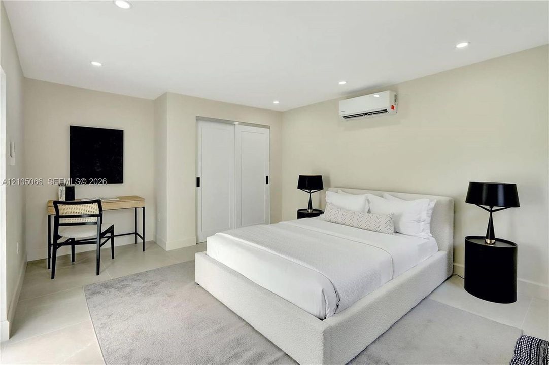 Neutral-toned interior featuring recessed lighting, a wall-mounted climate control unit, and double sliding closet doors