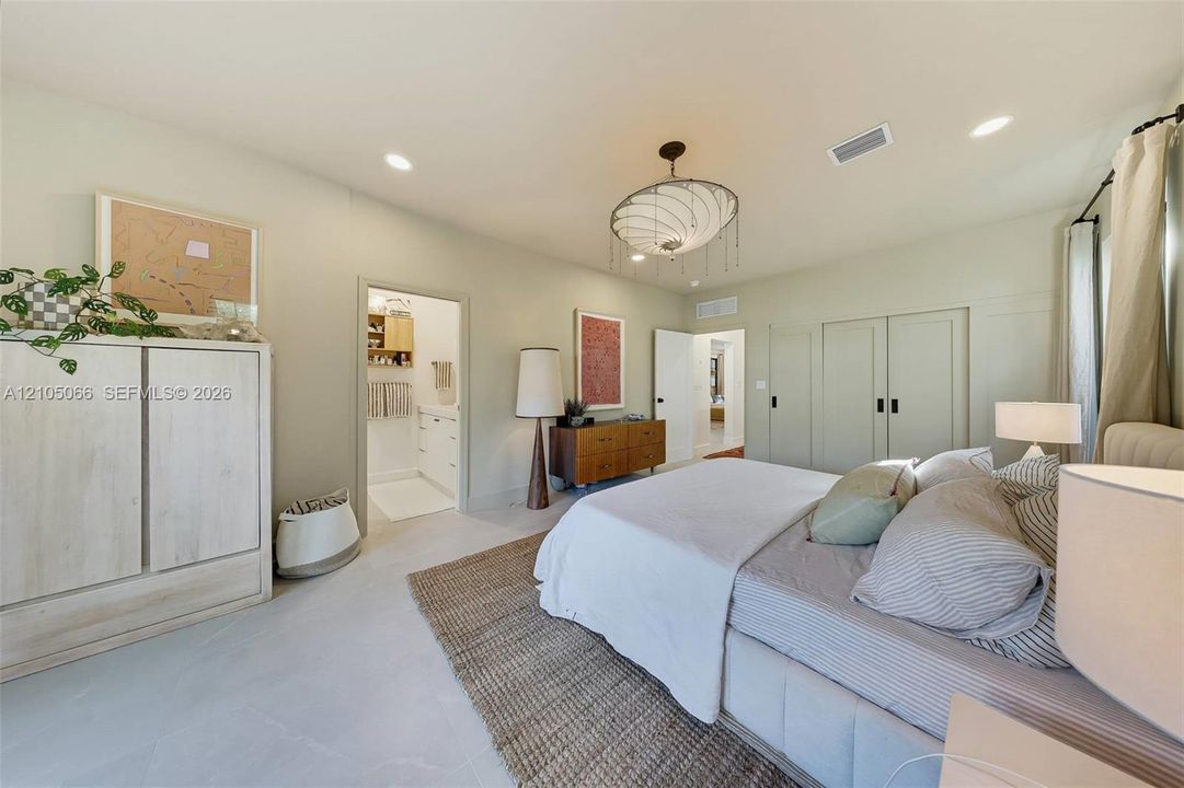 Bedroom featuring light-toned large-format tile flooring, recessed lighting, a modern multi-tiered chandelier, and floor-to-ceiling built-in cabinetry with matte black hardware