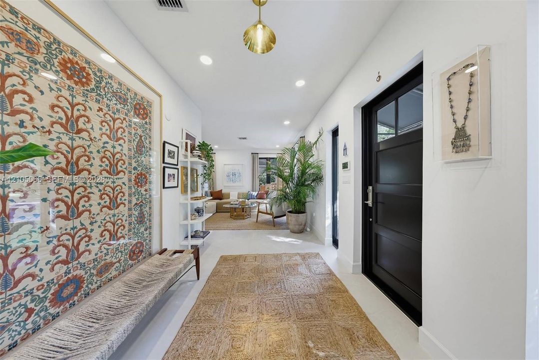Entryway featuring a black multi-panel door with glass inserts, recessed lighting, and a pendant fixture with a metallic finish
