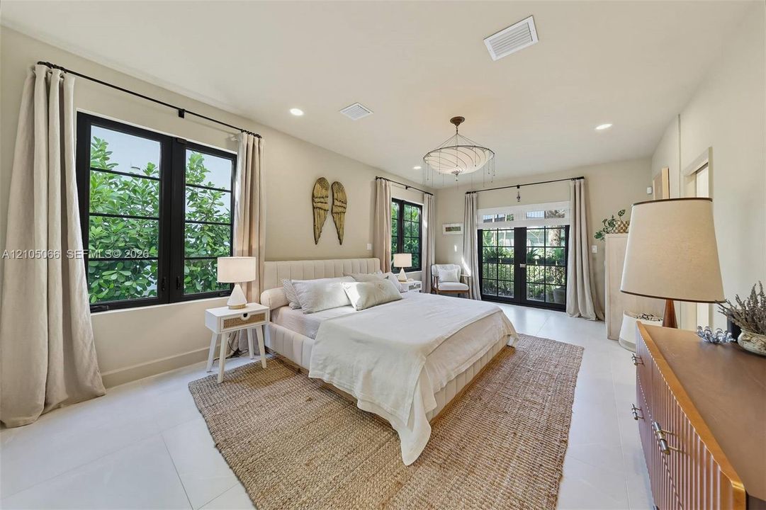 Neutral interior featuring large-format tile flooring, recessed lighting, a modern multi-tiered chandelier, black-framed windows, and a set of glass-paned double doors