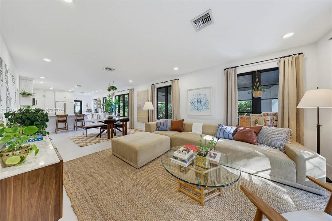 Open-concept interior featuring light-toned flooring, recessed lighting, and expansive windows with black frames