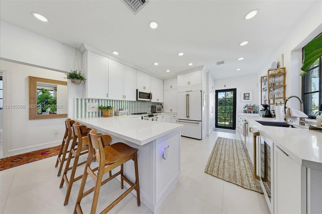 Kitchen featuring white cabinetry, quartz countertops, a striped backsplash, recessed lighting, and a built-in wine refrigerator