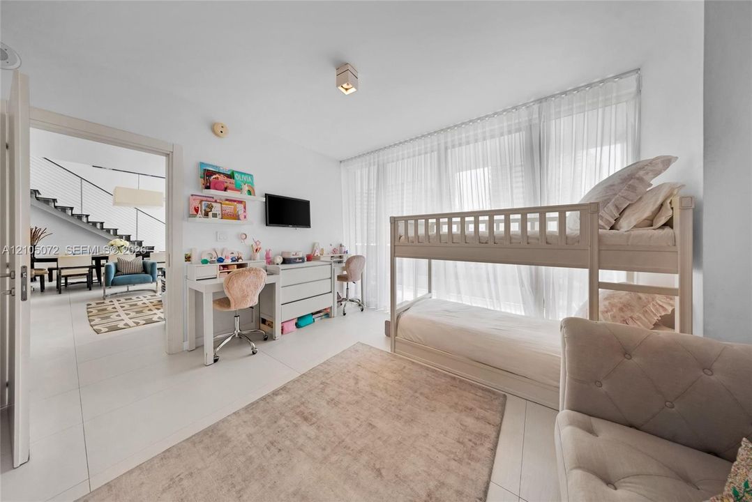 Secondary bedroom with bunk bed, study desk, and sheer curtains filtering daylight.