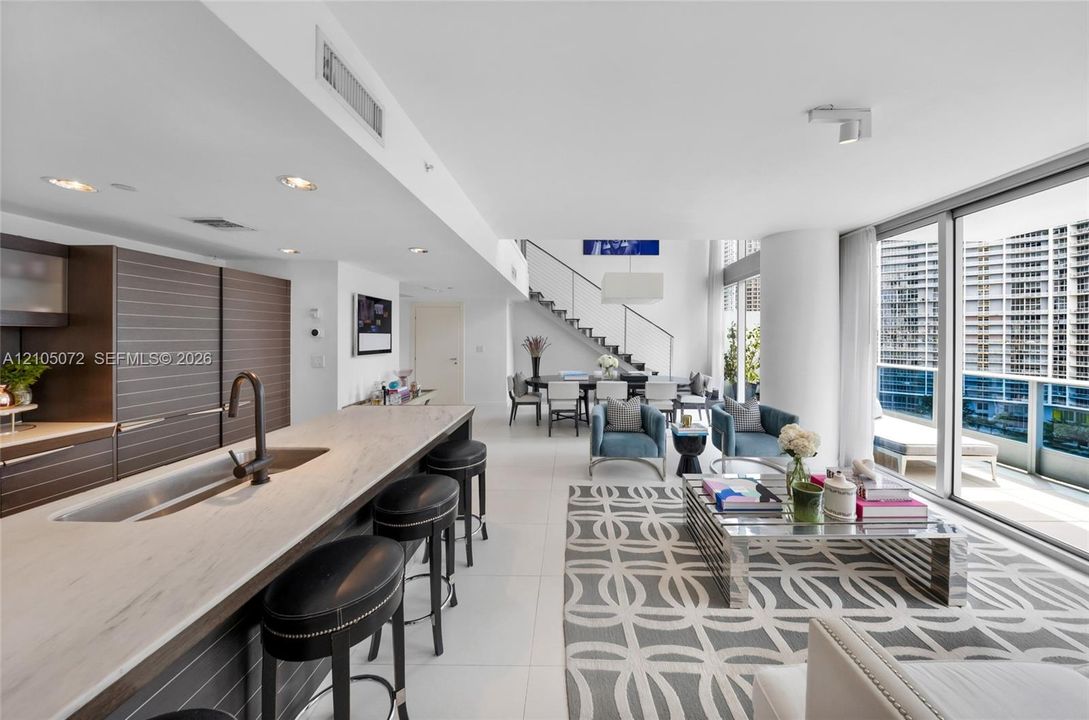 Kitchen island with Carrara marble counters and seating facing the open living room.
